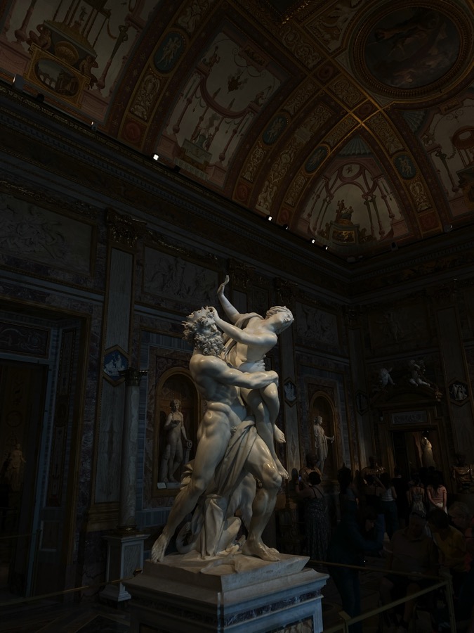 A white marble statue of The Abduction of Proserpina by Gian Lorenzo Bernini. Pluto has grabbed Proserpina who tries in vain to push him away.