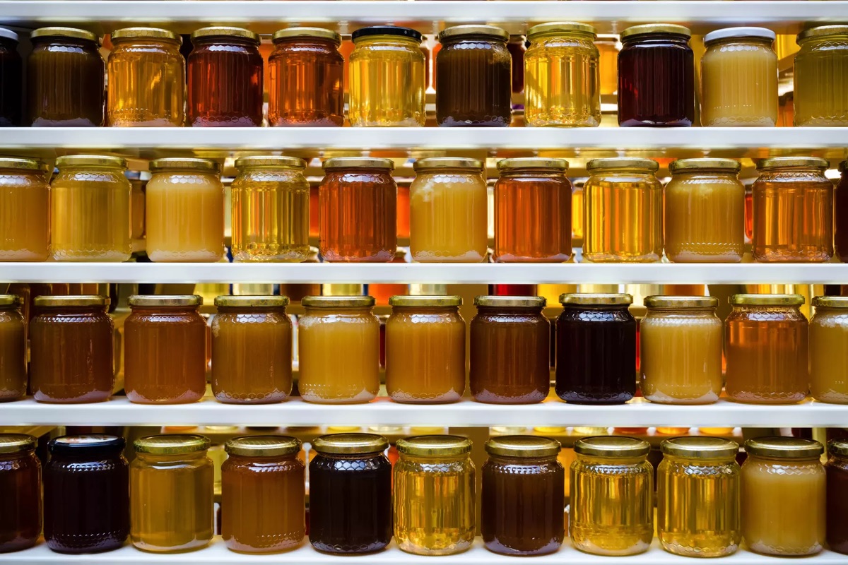 Clear jars of various honeys on shelves