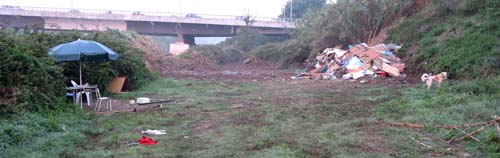 A panoramic view with an umbrella and table to one side and a huge heap of debris to the other.