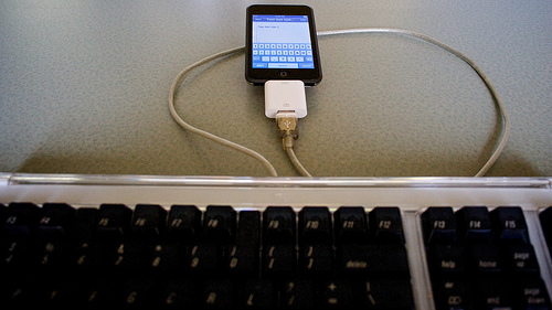 A full size keyboard attached by cable to something that looks like an iPod