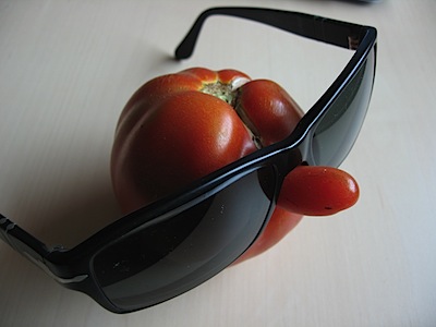 A tomato with a protruberance like a nose, wearing sunglasses