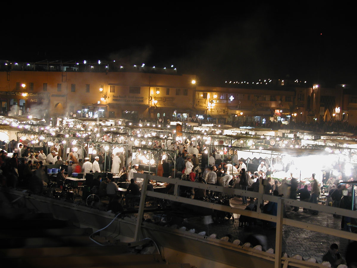 Jamaa el-Fna Square at night, crowded with people illuminated by hundreds of lightbulbs in the dark