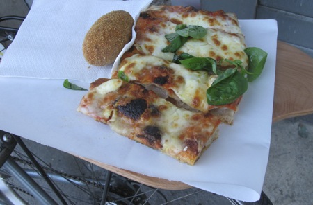 Wooden plate with a suppli and a slice of Bonci's pizza