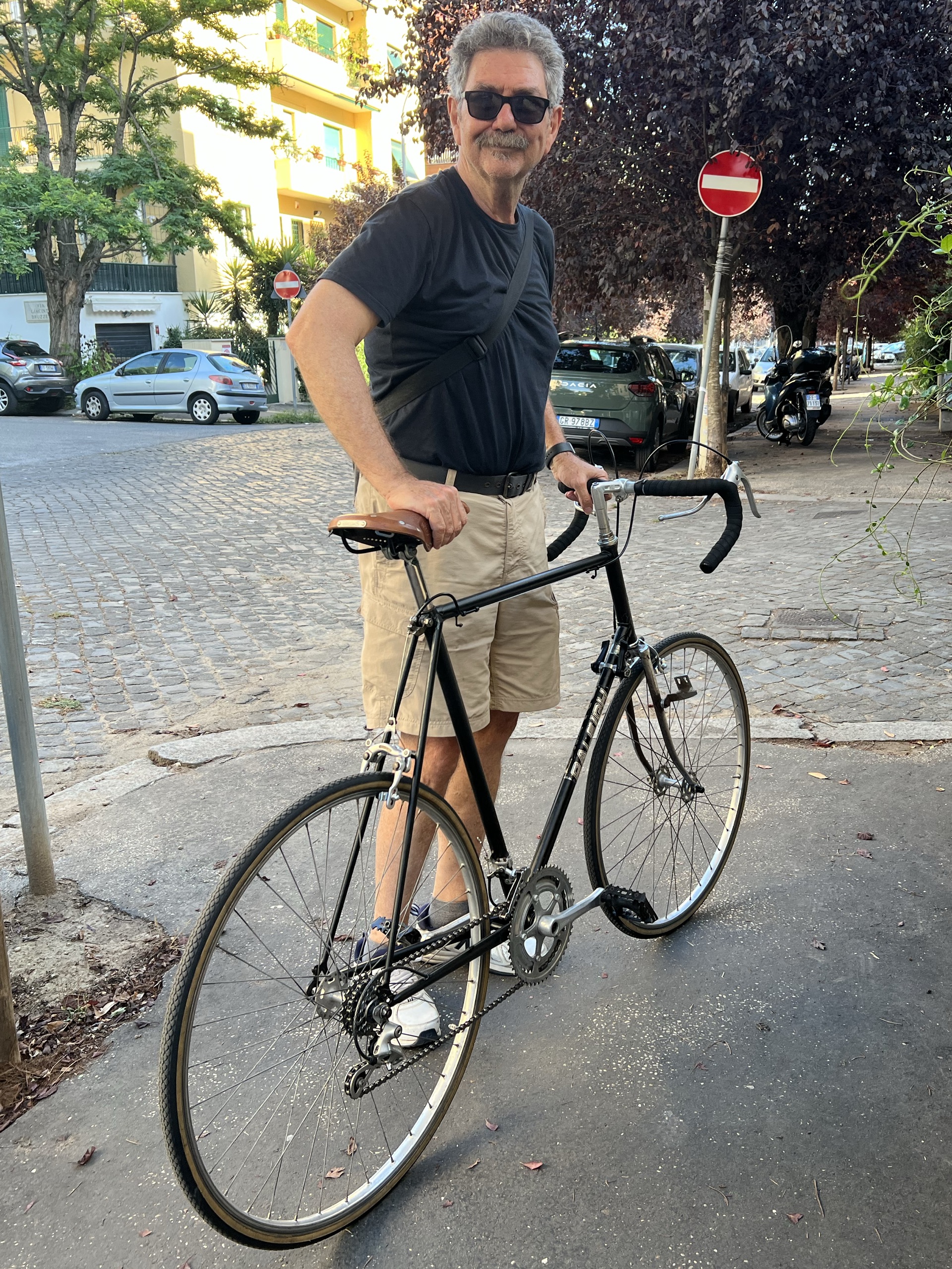 Me, wearing a black T-shirt and brown shorts, standing holding my refurbished Raleigh supressing almost idiotic grin.