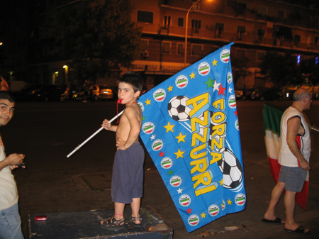 Young boy holding a giant flag celebrating the Italian football team