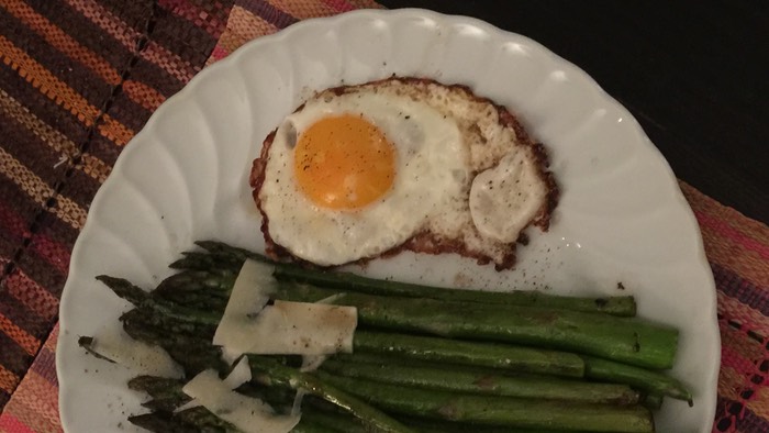 Asparagus with fried egg on the side and parmesan flakes